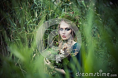 Beautiful fairy witch woman in green grass outdoors. Halloween character or Forest soul Stock Photo