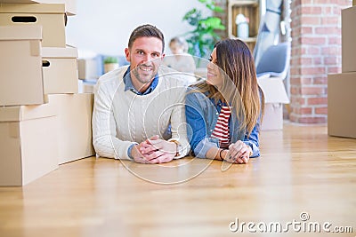 Beautiful famiily with kid lying down at new home around cardboard boxes Stock Photo