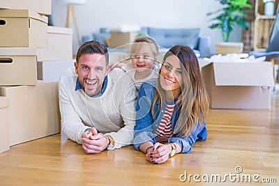 Beautiful famiily with kid lying down at new home around cardboard boxes Stock Photo