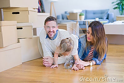 Beautiful famiily with kid lying down at new home around cardboard boxes Stock Photo