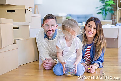 Beautiful famiily with kid lying down at new home around cardboard boxes Stock Photo