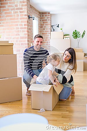 Beautiful famiily, kid playing with his parents riding cardboard fanny box at new home Stock Photo