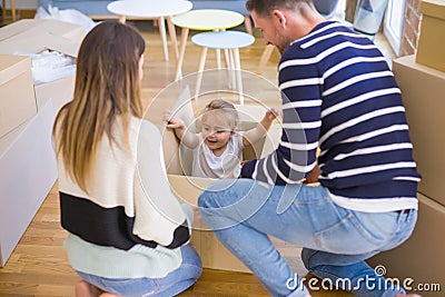 Beautiful famiily, kid playing with his parents riding cardboard fanny box at new home Stock Photo