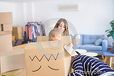 Beautiful famiily, kid playing with his parents riding fanny cardboard box at new home Stock Photo