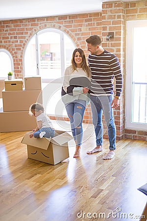 Beautiful famiily, kid playing with his parents riding fanny cardboard box at new home Stock Photo