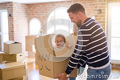 Beautiful famiily, kid playing with his parents riding fanny cardboard box at new home Stock Photo