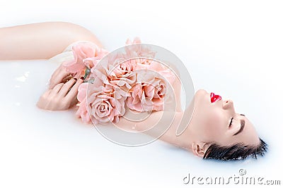 Beautiful Fashion model girl with bright makeup and pink roses taking milk bath Stock Photo