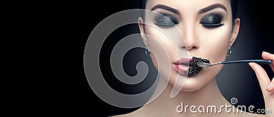 Beautiful fashion model woman eating black caviar. Beauty girl with caviar on her lips Stock Photo