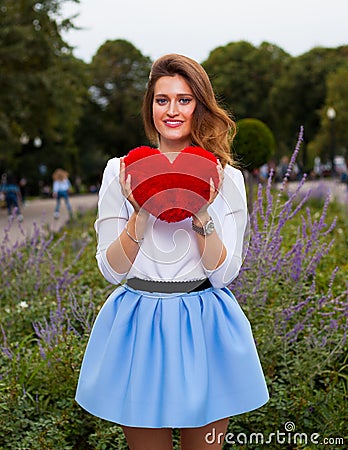 Beautiful fashionable Girl with red heart in the park in warm summer evening Stock Photo