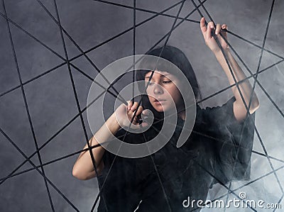 Beautiful fashionable lady wearing a gothic black dress with high collar, poses in white smoke on a grey background. Stock Photo