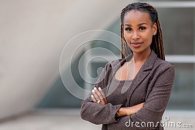 Beautiful female african american business woman CEO in a suit at the workplace, standing confidently with arms folded Stock Photo