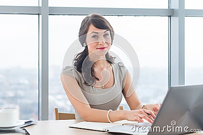 Beautiful female copywriter sitting in office, typing new article, working with text, using laptop at workplace. Stock Photo