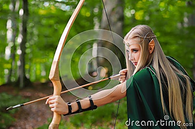 Beautiful female elf archer in the forest hunting with a bow Stock Photo