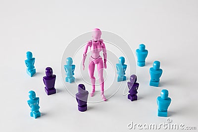Beautiful female figurine standing among faceles lookalike figurines. Search for identity concept. Stock Photo