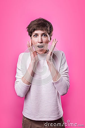 Beautiful female half-length portrait over pink studio backgroud. The young emotional smiling and surprised woman Stock Photo