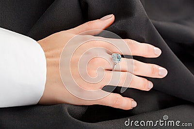 Beautiful female hand with gold ring with diamonds and emerald on gray background Stock Photo