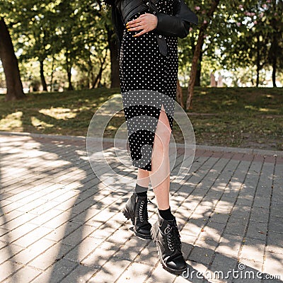 Beautiful female legs in fashionable black leather boots on a spring sunny day. pretty styled girl in a fashionable black dress Stock Photo