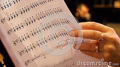Beautiful female music composer looking at music notes. Woman looks at notes on piano closeup Stock Photo