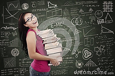 Beautiful female student bring stack of books in class Stock Photo