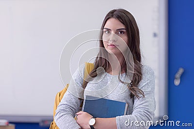 Beautiful female student at university campus interior holding book and smilling into camera Stock Photo