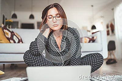 Beautiful female writer dressed pajamas typing notebook keyboard writing novel sitting cross-legged on living room floor with Stock Photo