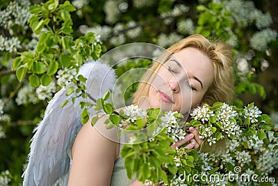 Beautiful feminime woman with white wings with white spring flowers. Stock Photo