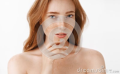 Beautiful feminine and attractive woman with natural red hair and freckles on face and body touching chin gently with Stock Photo