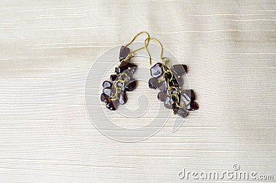 Beautiful, feminine, fashion earrings from brown dark stones, amber on a background of beige fabri Stock Photo