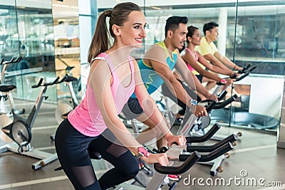 Beautiful fit woman smiling during cardio workout at indoor cycling class Stock Photo