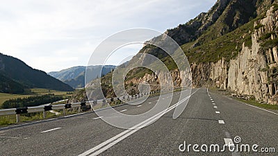 Beautiful flat empty asphalt road among the mountains. Accurate road markings. Traffic management in hard-to-reach places. Travel Stock Photo