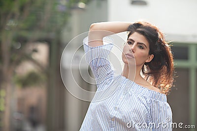 Beautiful flirty brunette playing with her hair on a alley of a city, shallow focus Stock Photo