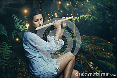 Beautiful forest nymph playing flute with fairies Stock Photo