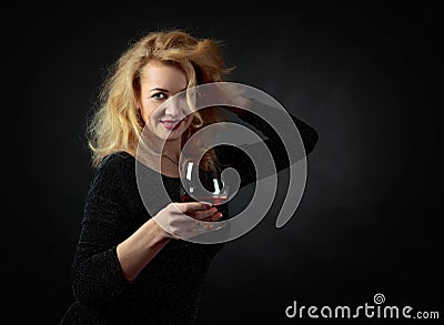 Beautiful forty years blonde in black evening dress with snifter of brandy Stock Photo