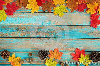 Beautiful frame composed of autumn maple leaves with pine cones on wood plank. Stock Photo