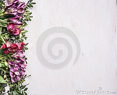 Beautiful freesya multicolored flowers with green leaves border ,place for text wooden rustic background top view Stock Photo