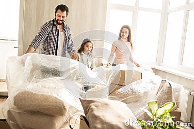 Beautiful and friendly family are unpacking their stuff. They are putting off the cover of boxes. There are lots of Stock Photo