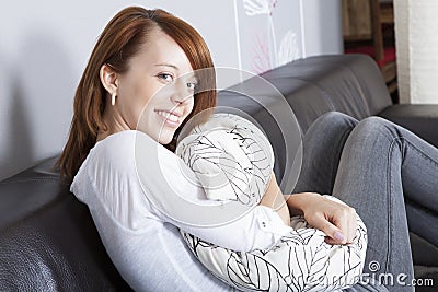 Beautiful friendly woman hugging a cushion Stock Photo