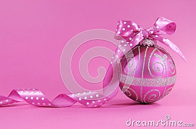 Beautiful fuchsia pink festive bauble ornament with polka dot ribbon on a feminine pink background with copy space Stock Photo