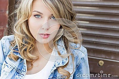 Beautiful funny blonde girl with big lips with a charming smile, wearing jeans and a white shirt walking in the city solnetsnym Stock Photo