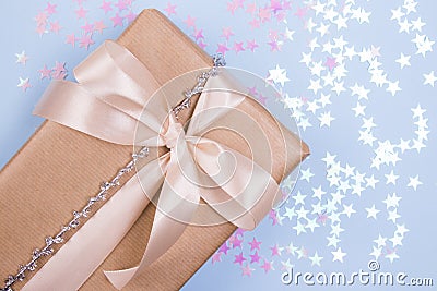 Beautiful gift box with beige bow and pink glitter stars on a pastel blue background. Flat lay Stock Photo
