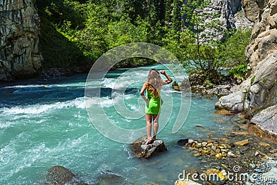 A beautiful girl on the bank of a mountain stream, Kyrgyzstan. Stock Photo