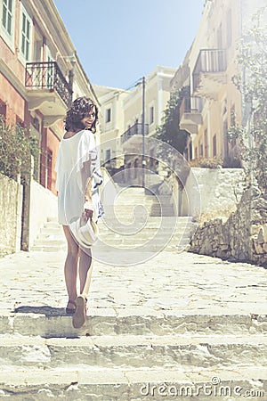 Beautiful girl bathed in sunshine walking in ancient city Symi Stock Photo