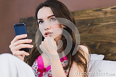 Beautiful girl in bed clicks on phone Stock Photo