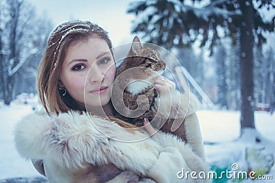 Beautiful girl in a beige short coat with flowing hair holding a cat Stock Photo