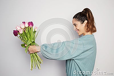 Beautiful girl with big bouquet flowers tulips in hands on a light background Stock Photo