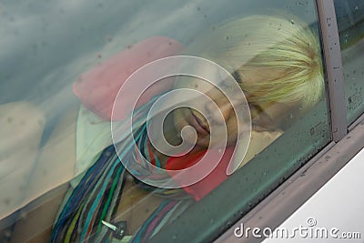 Beautiful girl with blonde hair taking a nap in the car on a rainy day Stock Photo