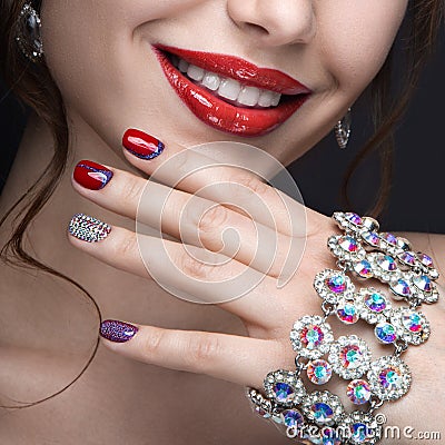 Beautiful girl with a bright evening make-up and red manicure with rhinestones. Nail design. Beauty face. Stock Photo