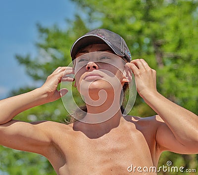 A beautiful girl in a cap straightens her hair. Stock Photo