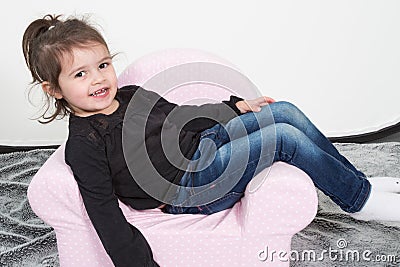 Girl child sitting on a pink children seat Stock Photo