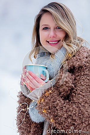 Girl in coat with cup of drink in a snow forest Stock Photo
